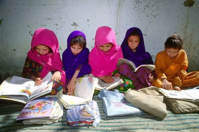 A sunlit classroom with notebooks and school bags on desks